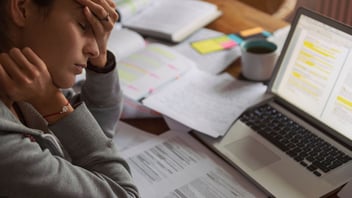 lady with hand in head burnout from over working papers on desk