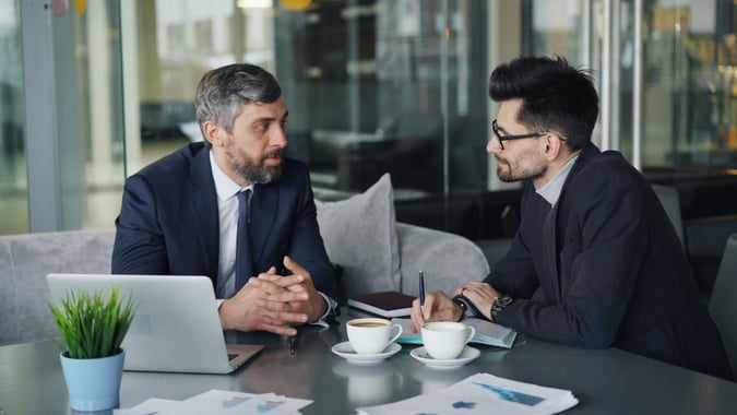 men talking at desk corporate