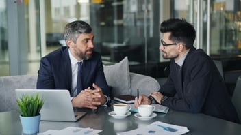 men talking at desk corporate