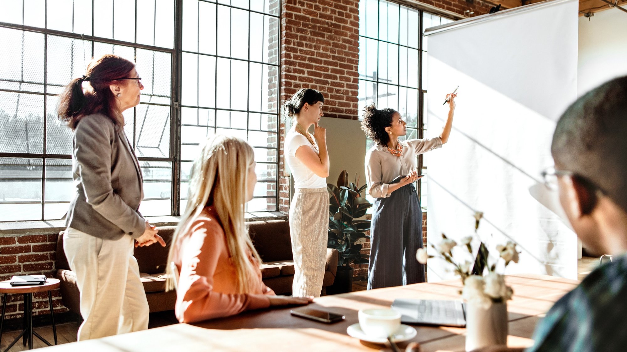 group of 5 professionals looking at someone writing on a white board