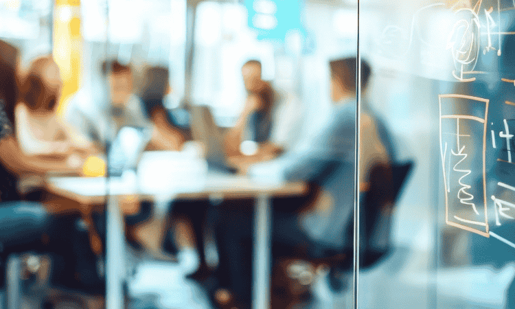 Blurry image of a group of people working together around a table in an office space.