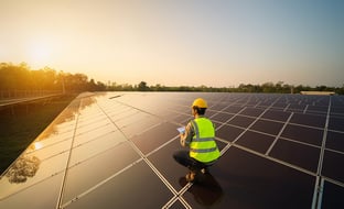 man on top of a large solar panel looking at the sunset