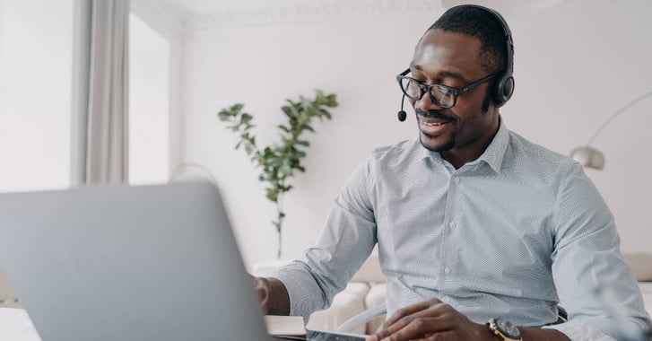 Man on laptop, talking on headset