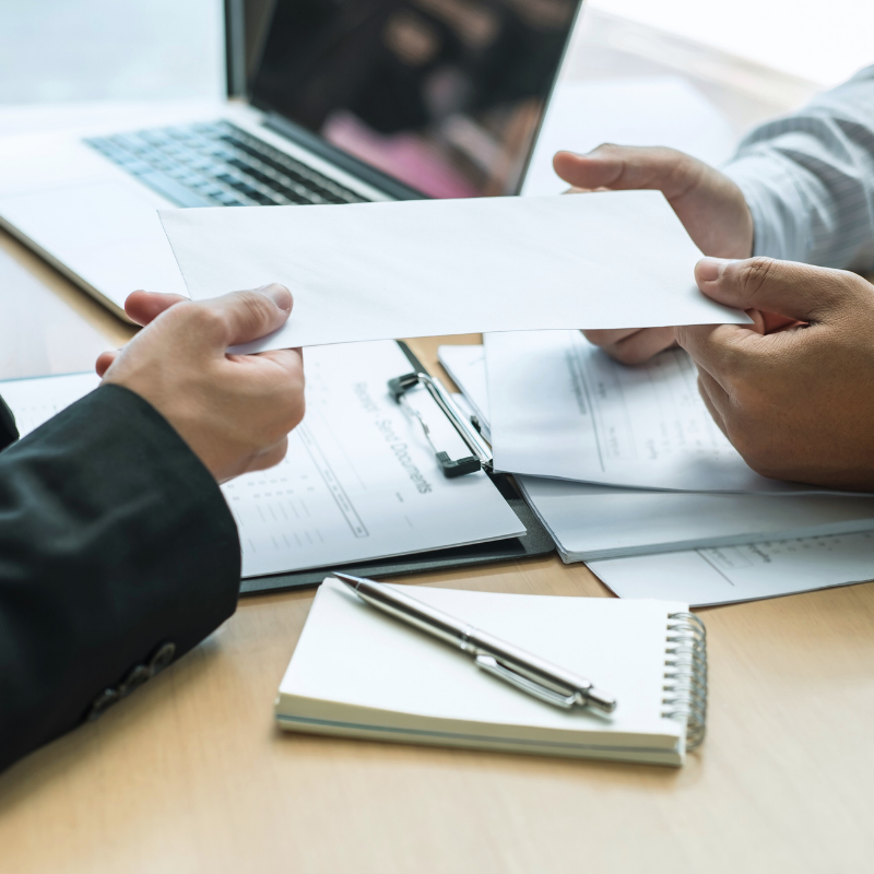 a person handing a resignation letter to their employer
