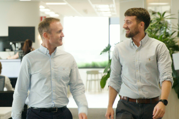 two men dressed professionally walking in an office