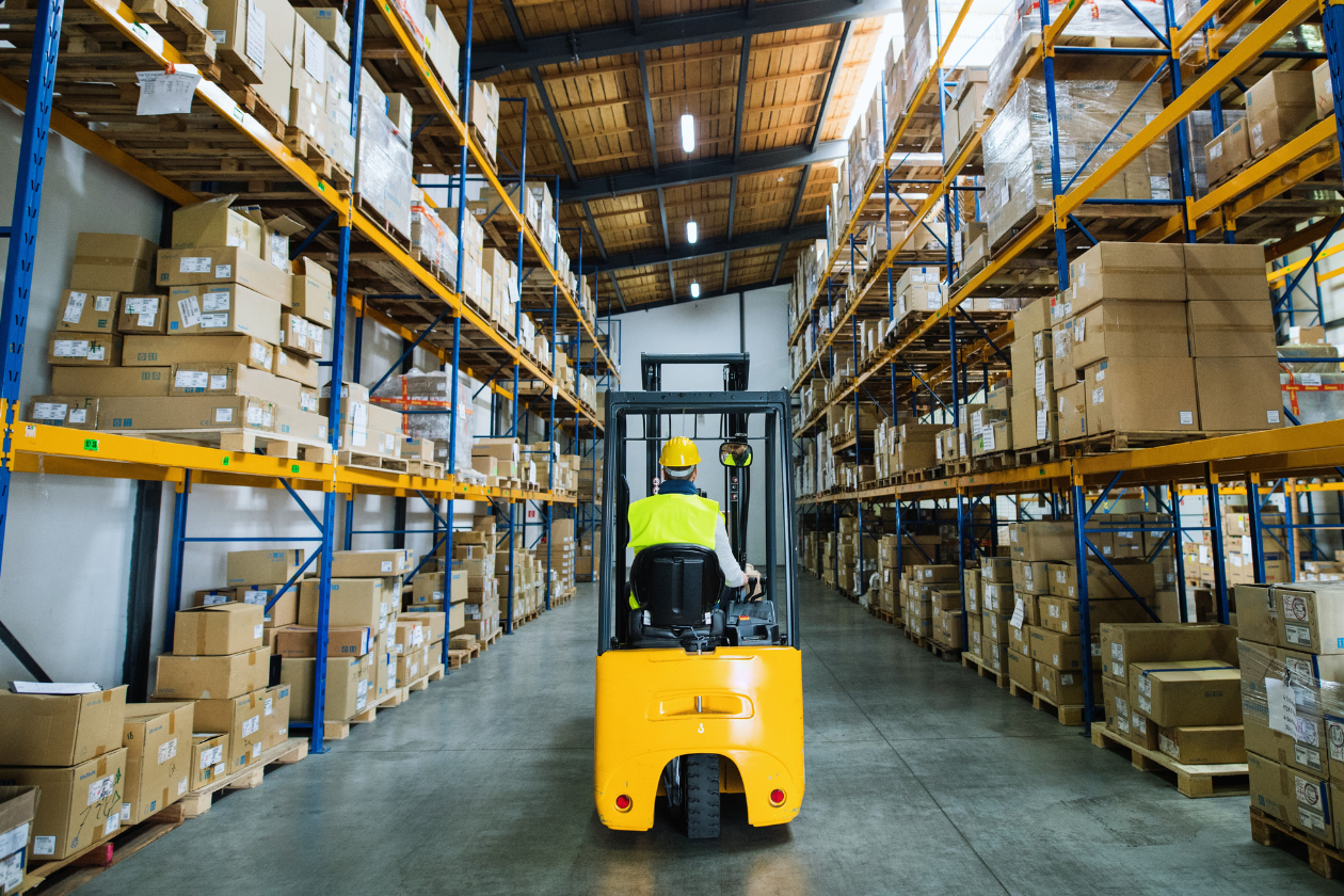 worker on vehicle driving in large warehouse