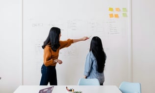 two women working from a white board