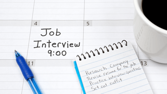 image showing with a calendar and a job interview date. A notepad next to it shows all the actions to do prior to the interview like researching the company.