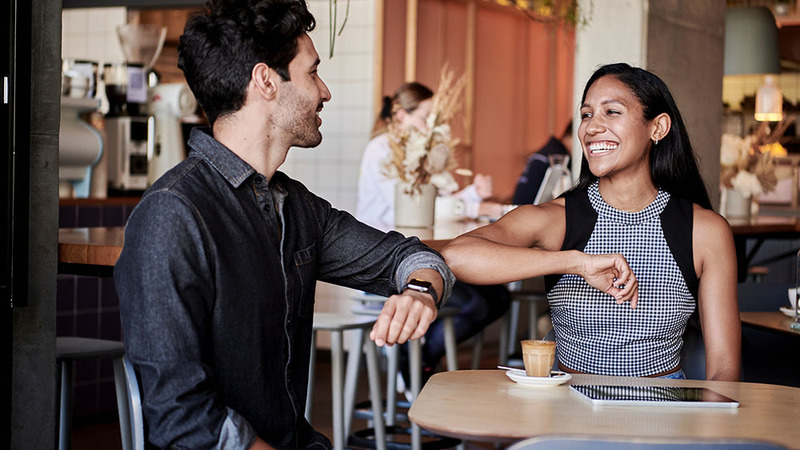 2 smiling employees bumping elbows together instead of a handshake