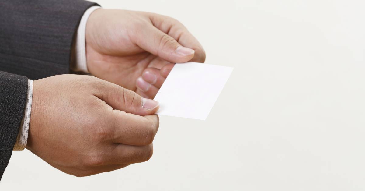 Man's hands hold a business card