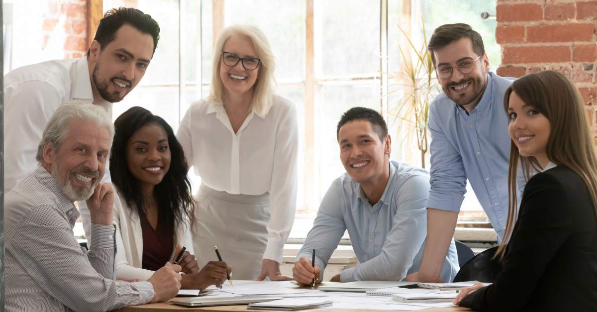 5 colleagues of different ages working around a desk