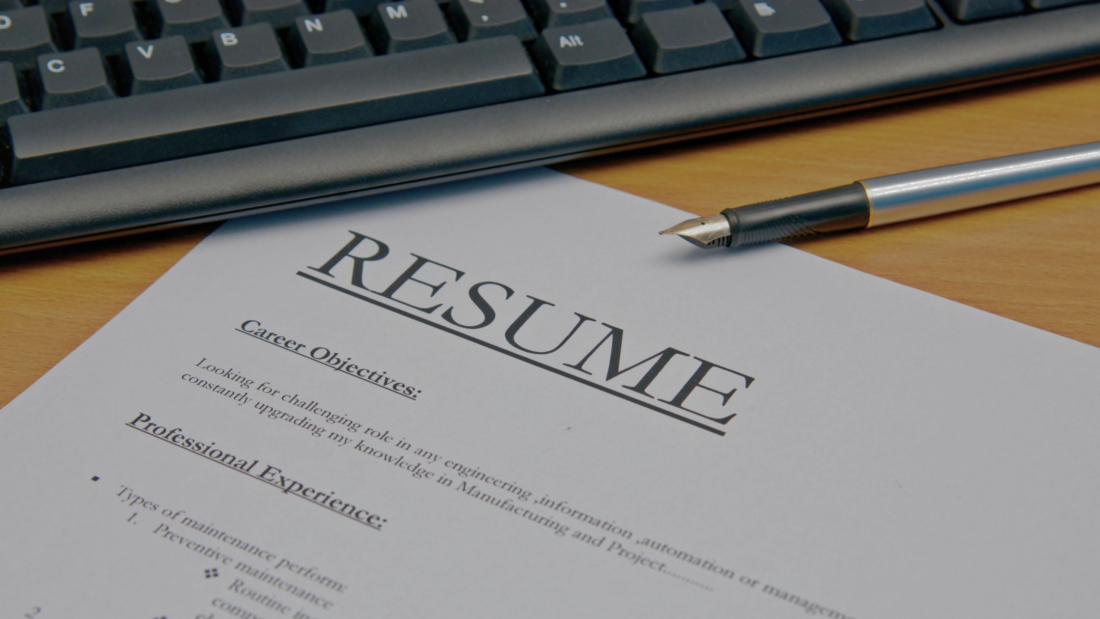 image of a resume, pen and keyboard on a table