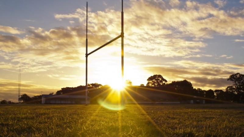 Sunrise behind rugby pitch revealing the goal posts