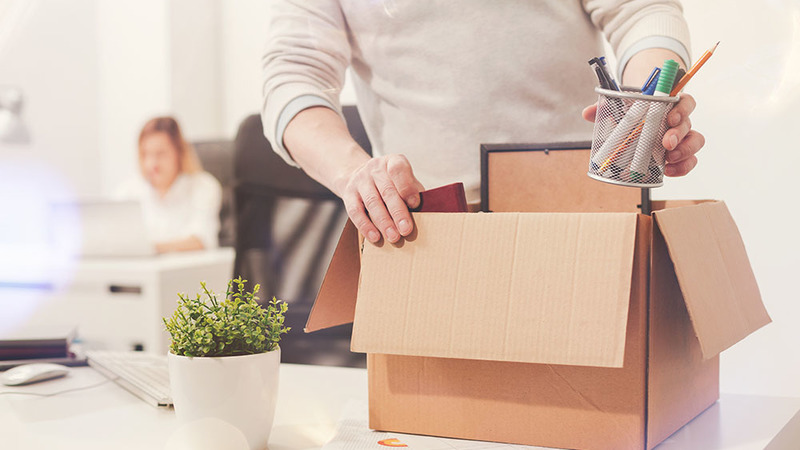 man packing his work belongings into cardboard box