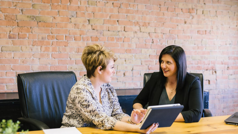 2 women in discussion sitting at a desk