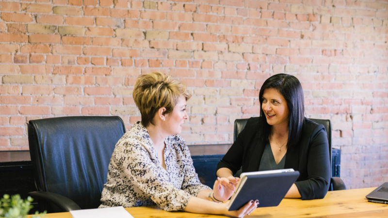 2 women in discussion sitting at a desk 